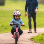 Kid riding on a Flamingo pink Airo 12 inch Balance bike
