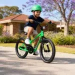 Six-year-old boy of Tongan heritage wearing a green helmet and riding a green Kidvelo Rookie 18 pedal bike in an Australian neighbourhood for Xchange Sports Australia.